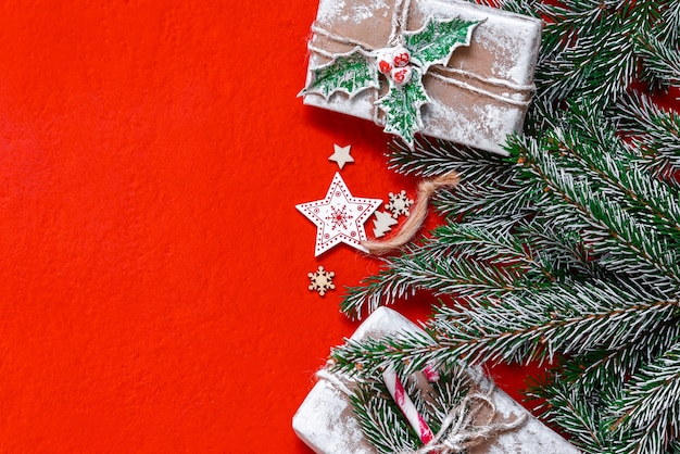 Conceito de presente de Natal em um fundo vermelho com enfeites e galhos de pinheiro.