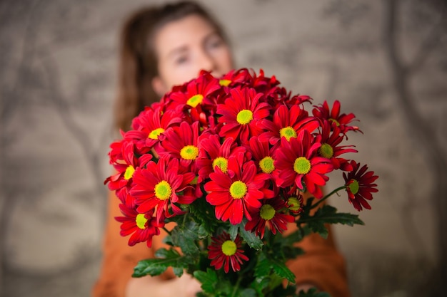 Conceito de presentes, celebração e ternura. Jovem fofa surpresa segurando um buquê de flores vermelhas, margaridas para o dia dos namorados