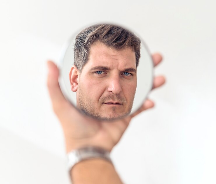 Conceito de procedimentos antiidade e saúde masculina homem maduro olha em um espelho cosmético redondo
