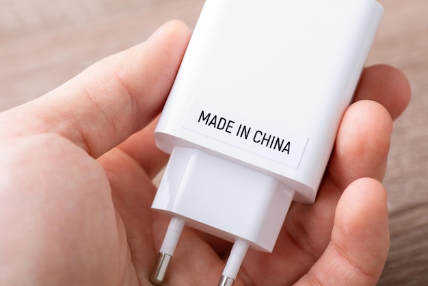 Conceito de produção de eletrônicos na China Homem segurando carregador de telefone com inscrição Made in China