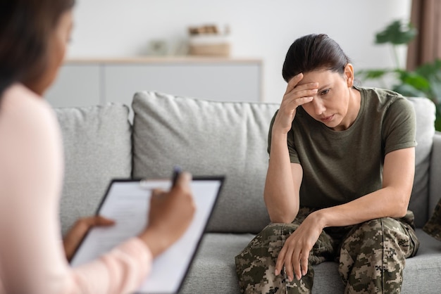 Conceito de psiquiatria militar deprimido soldado senhora sentada no sofá durante a sessão de terapia