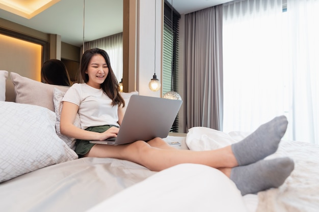 Conceito de quarto na cama confortável de uma adolescente do sexo feminino com seus dispositivos eletrônicos, o laptop e o smartphone.