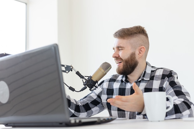 Conceito de rádio, dj, blog e pessoas - homem sorridente sentado em frente ao microfone, apresentador de rádio