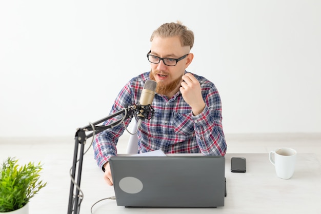 Conceito de rádio, DJ, blog e pessoas - homem sorridente sentado em frente ao microfone, apresentador de rádio