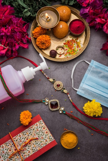 Conceito de raksha bandhan ou rakhi festival em corona virus ou covid-19 pandemic mostrando rakhi / raakhi / pulseira com desinfetante e máscara facial médica por precaução