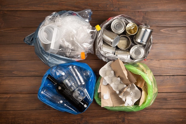 Conceito de reciclagem e ecologia Separação de resíduos domésticos de plástico papel metal capturado de cima plano fundo de madeira