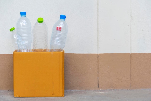 Foto conceito de reciclagem garrafas plásticas vazias colocadas em uma caixa de papel pardo espaço em branco para inserir texto