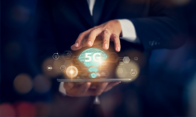 Conceito de rede futura tecnologia 5G, mãos de empresário segurando o tablet e interface de tela de redes de alta velocidade nova geração. Sistemas sem fio e internet das coisas (IOT).