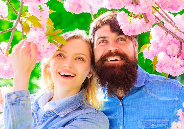 Conceito de relacionamento. Casal feliz perto do florescimento de Sakura. Família sorridente passa algum tempo no jardim primavera.