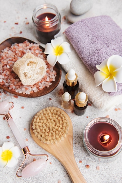 Conceito de relaxamento de belo spa. Escova para massagem corporal, toalhas, velas e sal marinho em fundo de pedra cinza.