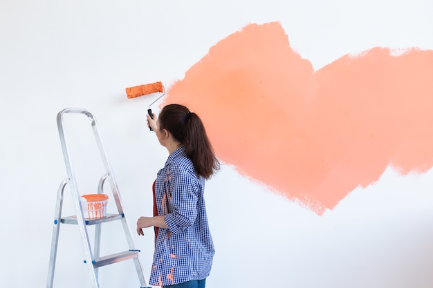 Conceito de renovação, redecoração e reparação. Parede de pintura de mulher alegre na nova casa. Copie o espaço.