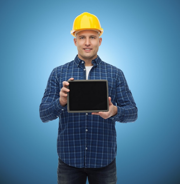 conceito de reparação, construção, construção, pessoas e manutenção - sorridente construtor masculino ou trabalhador manual no capacete mostrando a tela em branco do computador tablet pc sobre fundo azul