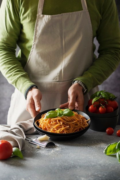 Conceito de restaurante. homem cozinhando espaguete italiano com tomate e manjericão, imagem de foco seletivo