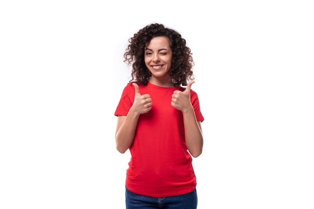 Foto conceito de roupa corporativa jovem sorridente mulher morena encaracolada em camiseta vermelha em fundo branco com