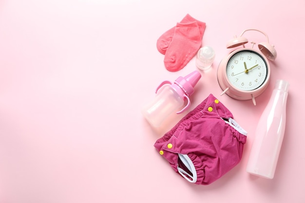 Conceito de roupa de bebê com fraldas reutilizáveis em fundo rosa