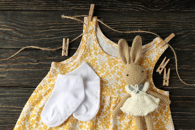 Foto conceito de roupas de bebê feminino em fundo de madeira.