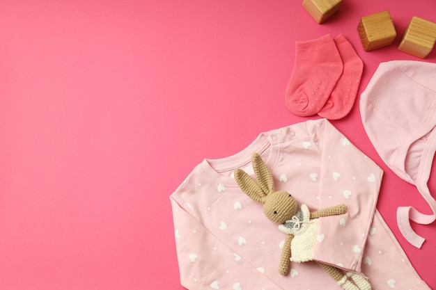 Conceito de roupas de bebê feminino em fundo rosa.