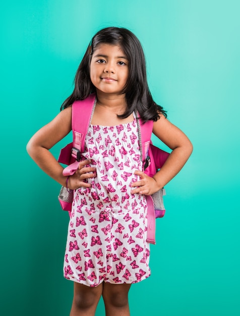 Conceito de saída para a escola - menina indiana bonitinha em pé com uma bolsa escolar, isolada sobre um fundo verde