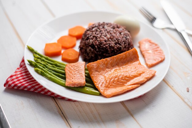 Conceito de saúde alimentar, salmão com arroz e vegetais no fundo de madeira