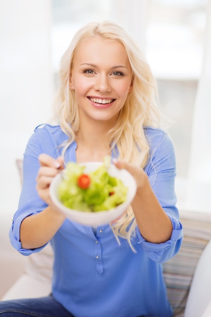 conceito de saúde, dieta, lar e felicidade - jovem sorridente com salada verde em casa