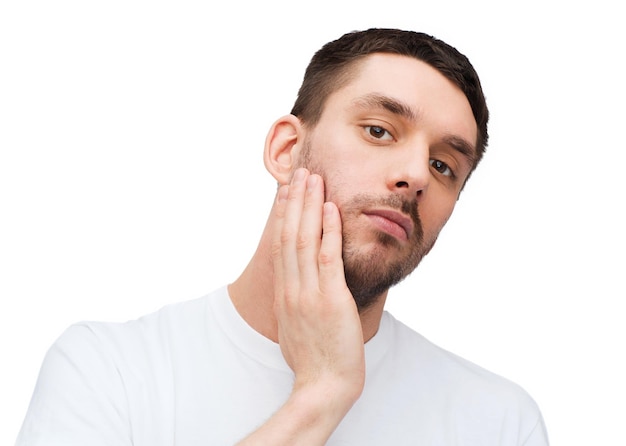 conceito de saúde e beleza - belo homem calmo tocando seu rosto