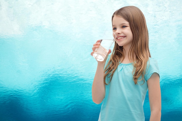 conceito de saúde e beleza - menina sorridente com copo de água