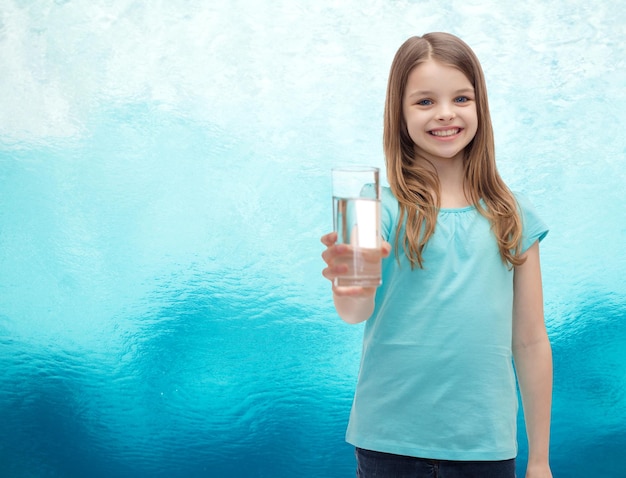 Conceito de saúde e beleza - menina sorridente dando o copo de água