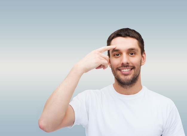 conceito de saúde e beleza - sorridente jovem bonito apontando para a testa