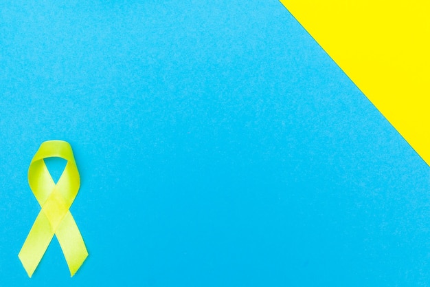 Foto conceito de saúde e medicina fita amarela de conscientização sobre o câncer com trilha em fundo azul