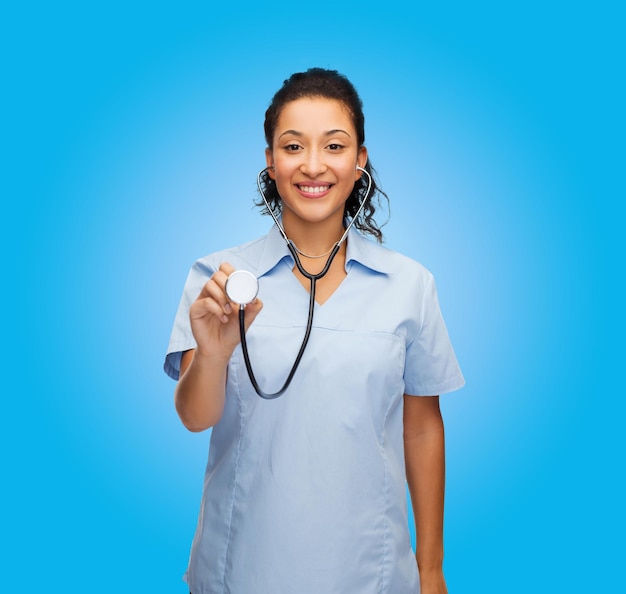 conceito de saúde e medicina - médica afro-americana sorridente ou enfermeira com estetoscópio