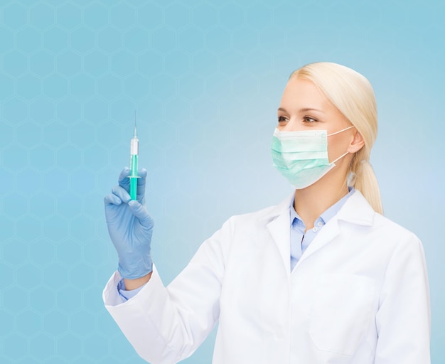 conceito de saúde e medicina - médica em máscara e luvas segurando seringa com injeção sobre fundo azul