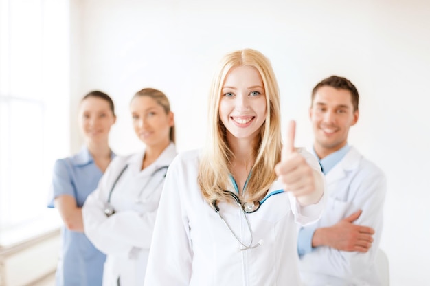 conceito de saúde e medicina - médica ou enfermeira atraente na frente do grupo médico no hospital mostrando os polegares para cima