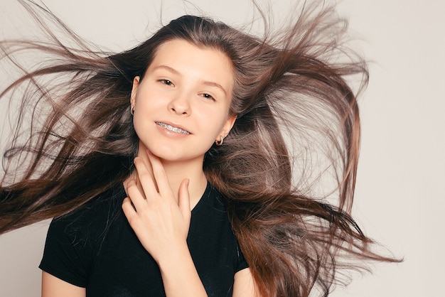 Conceito de saúde, pessoas, dentista e estilo de vida - retrato de uma adolescente mostrando o aparelho dentário. retrato sincero de uma menina de aparelho, com movimento do cabelo. garota rindo usando aparelho ortodôntico, retrato alegre