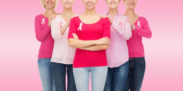 Foto conceito de saúde, pessoas e medicina - close-up de mulheres sorridentes em camisas em branco com fitas de conscientização de câncer de mama sobre fundo rosa