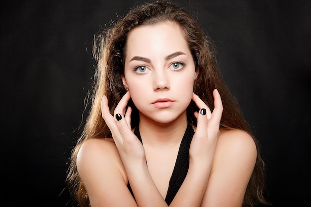 Foto conceito de saúde, pessoas, juventude e beleza - retrato de mulher de beleza. maquiagem profissional para morena de olhos azuis - batom vermelho. rosto de menina linda modelo de moda. isolado em um fundo preto.