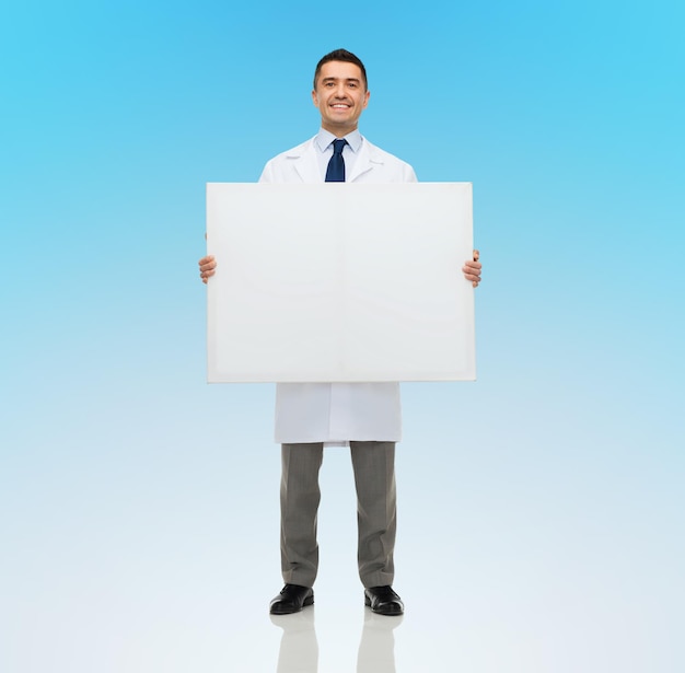 conceito de saúde, propaganda, pessoas e medicina - médico ou cientista masculino sorridente de jaleco branco segurando uma placa branca em branco sobre fundo azul