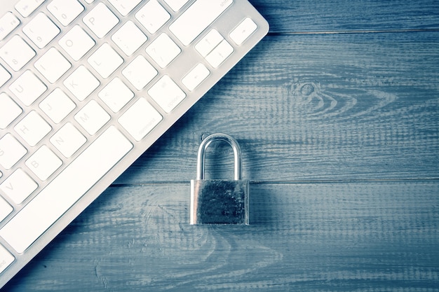 Conceito de segurança do computador. Cadeado desbloqueado no teclado do laptop. Símbolo de segurança. Foco seletivo na mesa de madeira cinza