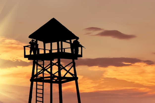 Conceito de segurança. silhueta de uma torre de vigia com soldados ao pôr do sol