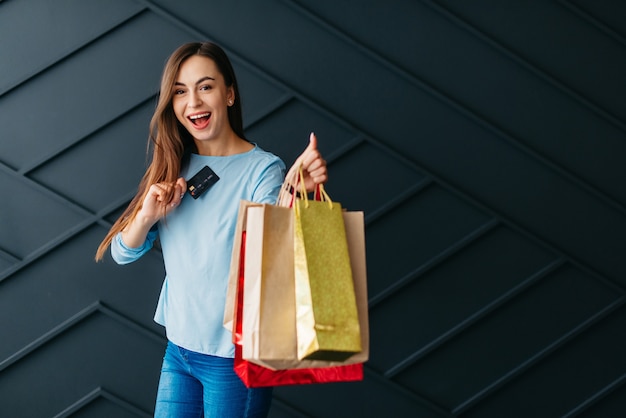 Conceito de sexta-feira negra, mulher alegre com cartão de pagamento e sacolas de compras nas mãos