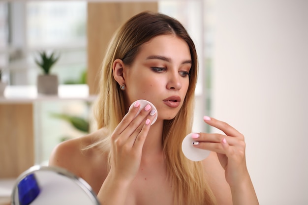 Conceito de skincare, retrato de mulher feliz aplicando creme cosmético no rosto