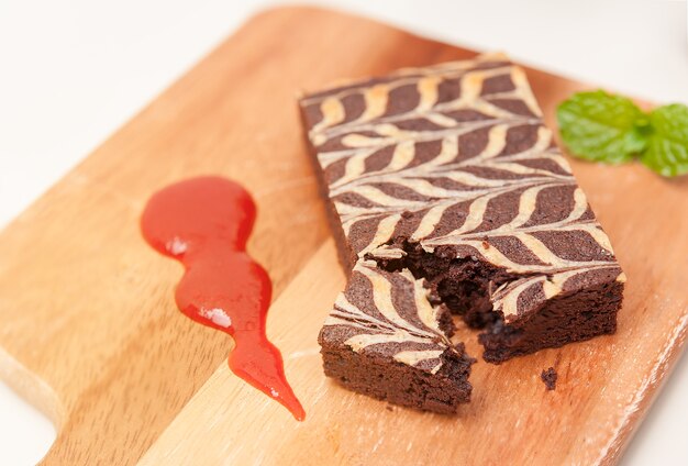 Conceito de sobremesa saudável, baixo teor de gordura Brownie na placa de madeira com molho de morango