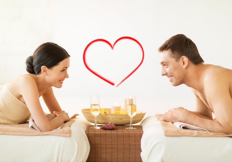 Foto conceito de spa, beleza, amor e felicidade - casal sorridente com velas no salão spa bebendo champanhe