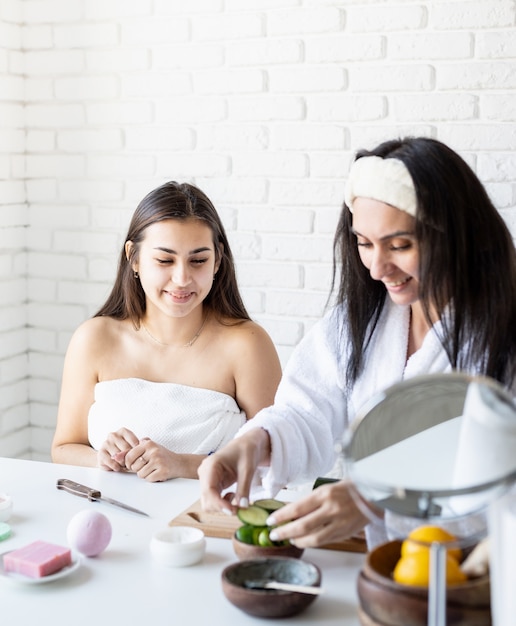 Conceito de spa e bem-estar. Autocuidados. duas lindas mulheres fazendo procedimentos de spa cortando pepinos