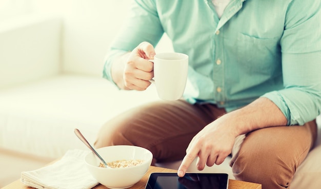 conceito de tecnologia, casa, bebidas, comida e estilo de vida - close-up do homem com computador tablet pc e café tomando café da manhã em casa