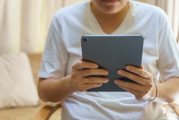 Conceito de tecnologia. Closeup de tablet de computador em mão de homem asiático na sala de estar