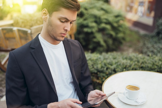 Conceito de tecnologia e comunicação Elegante estudante caucasiano navegando na internet em tablet digital desfrutando de conexão sem fio gratuita no café durante o coffee break Mensagens masculinas bonitas online