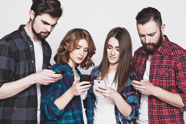 Foto conceito de tecnologia e internet: grupo de jovens olhando para seus smartphones