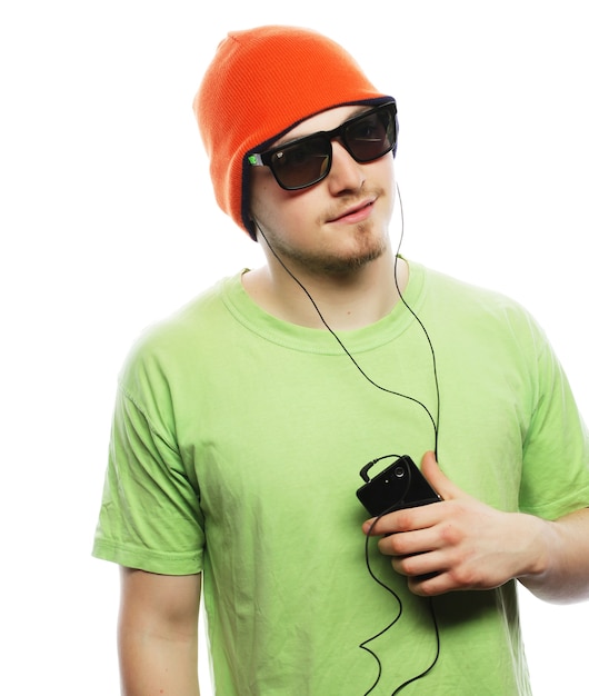 Conceito de tecnologia e pessoas - jovem vestindo camiseta verde, ouvindo música e usando smartphone, isolado no branco
