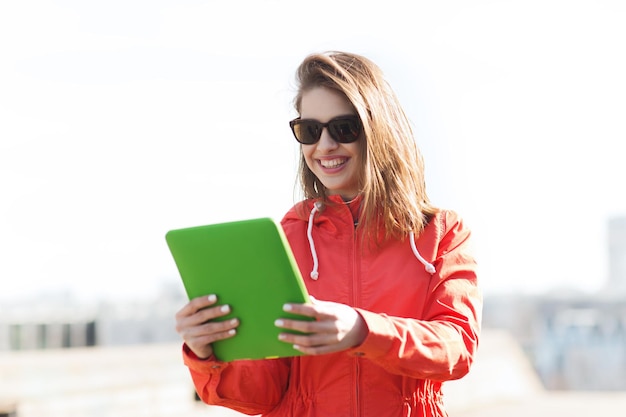 conceito de tecnologia, estilo de vida e pessoas - jovem sorridente ou adolescente com computador tablet pc ao ar livre
