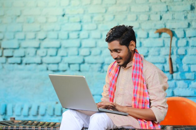 Conceito de tecnologia: fazendeiro indiano usando laptop em casa.